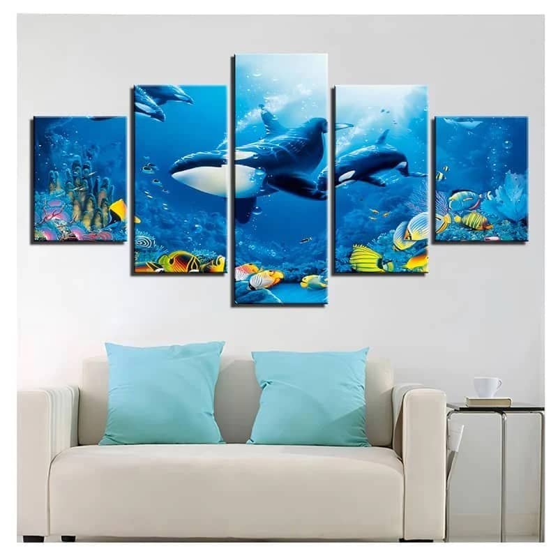 Five-piece wall art featuring an underwater scene with orcas and colorful fish, mounted above a white sofa with blue pillows.