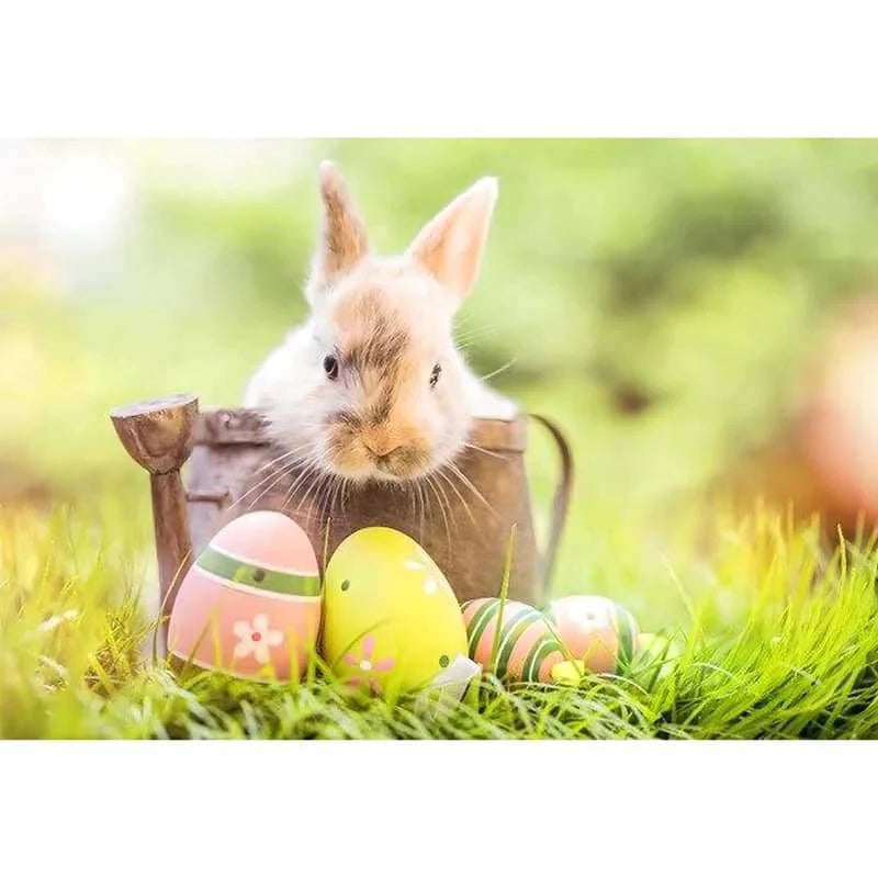 Cute bunny with painted Easter eggs in grass.