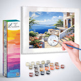 Paint by Numbers Mediterranean Dream kit with hand painting detailed seaside buildings and vibrant colors, including pink bougainvilleas.