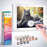 Paint by Numbers kit featuring a grey kitten resting on a blue velvet cushion, surrounded by golden curtains and orange flowers.