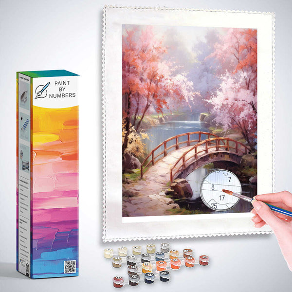 Paint by Numbers kit featuring "Bridge to the Enchanted" with pink and white flowers, wooden bridge over still water, promoting peaceful moods.