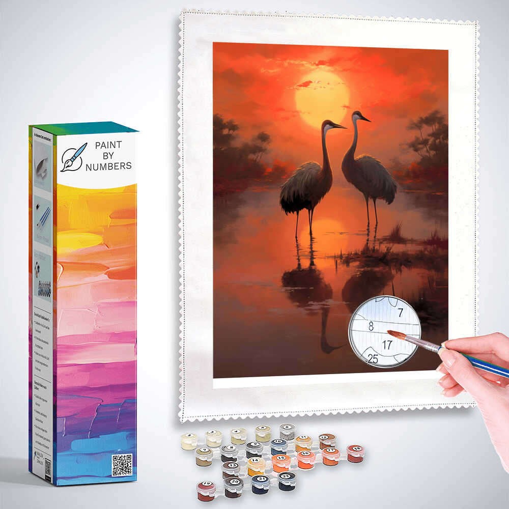Paint by Numbers kit of two cranes at sunset with a warm red and golden sky reflecting on the water, evoking harmony and peace.