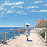 Girl in blue dress and white hat walking on sunlit path by a Mediterranean house with blue sea and clouds in the background - Paint by Numbers