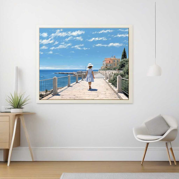 Paint by Numbers - Coastal Whispers artwork featuring a girl in a blue dress and hat walking along a Mediterranean path by the sea.