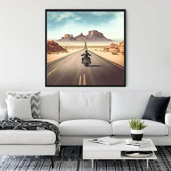 Wall art of motorcycle on desert road displayed above sofa in modern living room.