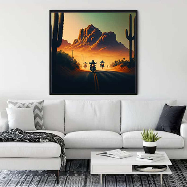 Diamond Painting - Asphalt Cowboy framed artwork featuring motorcyclist on a desert road at sunset displayed above a white sofa in modern living room.