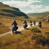 Five motorcyclists riding through a scenic, grassy landscape on a sunny day