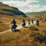 Five motorcyclists riding through a scenic, grassy landscape on a sunny day