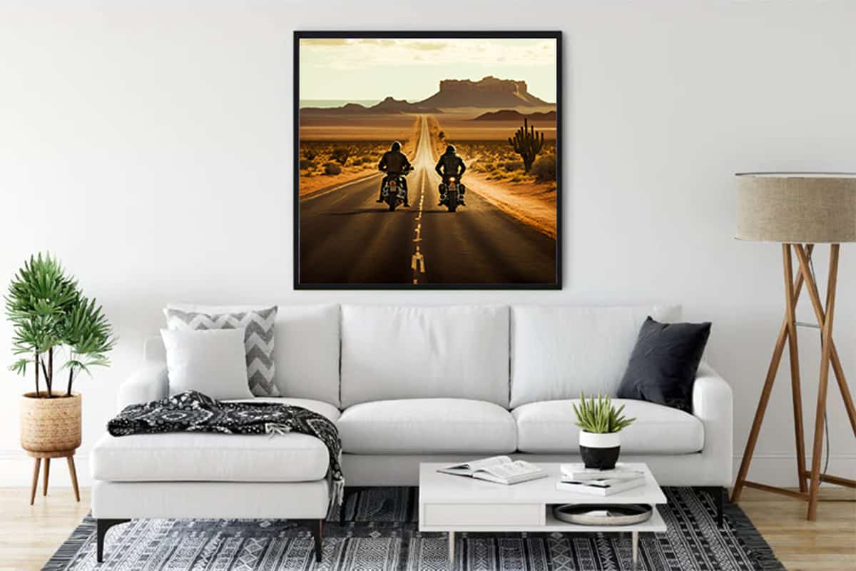 Wall art of two bikers riding on a desert road, displayed above a modern white sofa in a stylish living room.