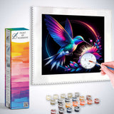 Paint by Numbers kit featuring a colorful diamond painting of a hummingbird with vibrant wings feeding on a purple flower against a black background.