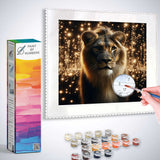 Paint by Numbers - Sternenmähne with lion surrounded by starry lights, showing paint kit and hand working on canvas