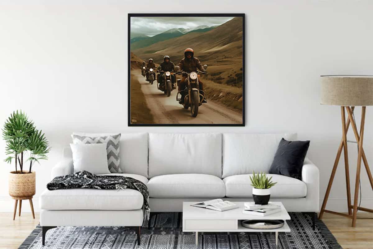 Framed Diamond Painting of motorcyclists riding through mountains in a modern living room above a white sofa.