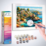 Paint by Numbers - Mediterranean Whispers kit showcasing a hand painting a Mediterranean village scene with paints and brushes.