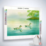 Diamond painting of two ducks on a serene lake with trees in the background; complete kit includes canvas, acrylic diamonds, tweezers, and pen.