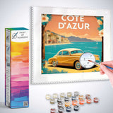 Paint by Numbers kit showcasing a vintage car on the Côte d'Azur with soft orange and blue hues, surrounded by paint colors and brushes.